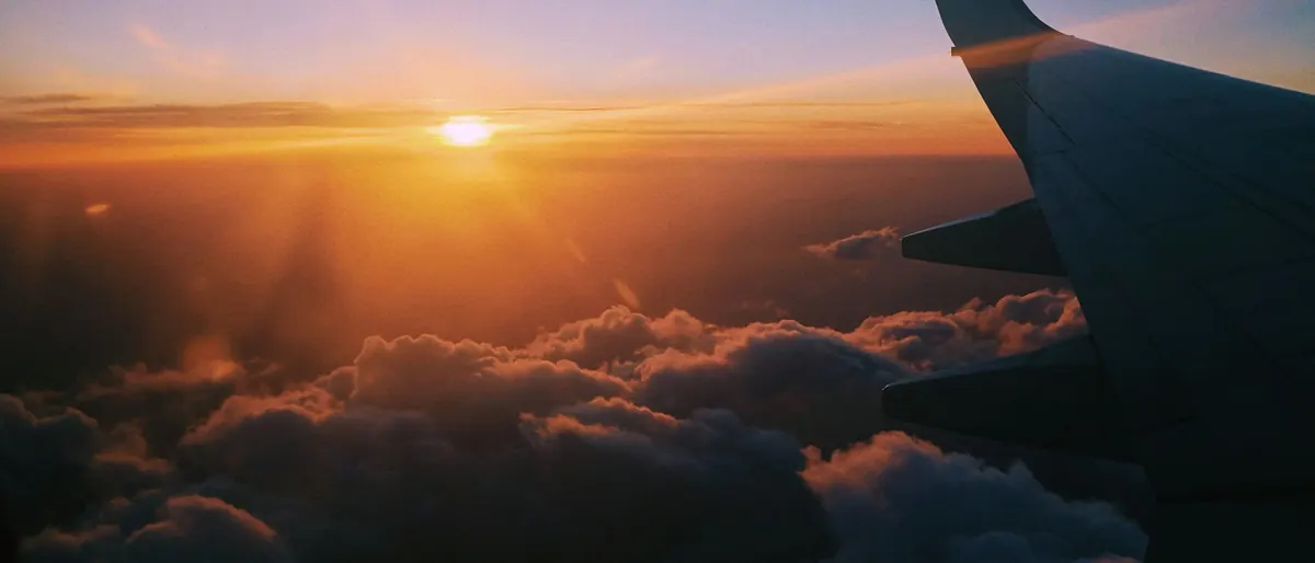 Aircraft wing above sunset clouds