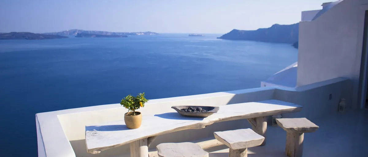 Whitewashed terrace table above a deep blue sea in the Cyclades