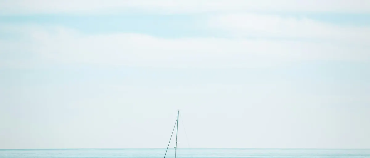 A lone sailboat on open turquoise water