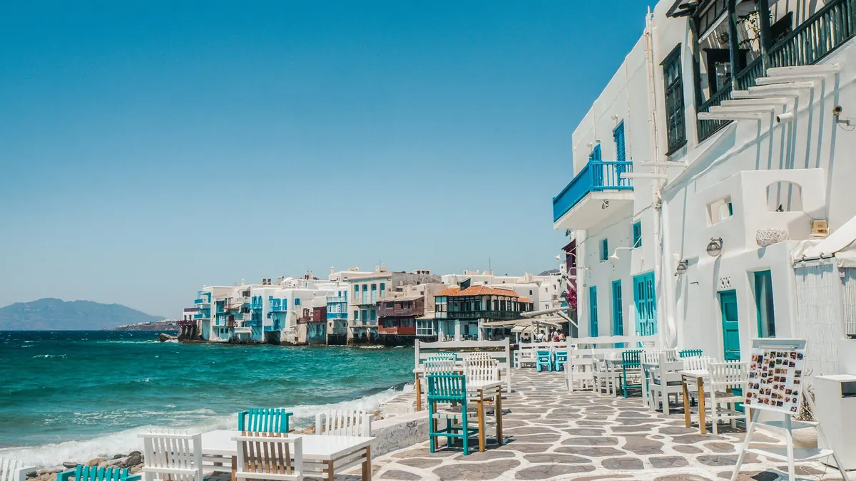 Café tables on a stone terrace beside the sea in Little Venice, Mykonos