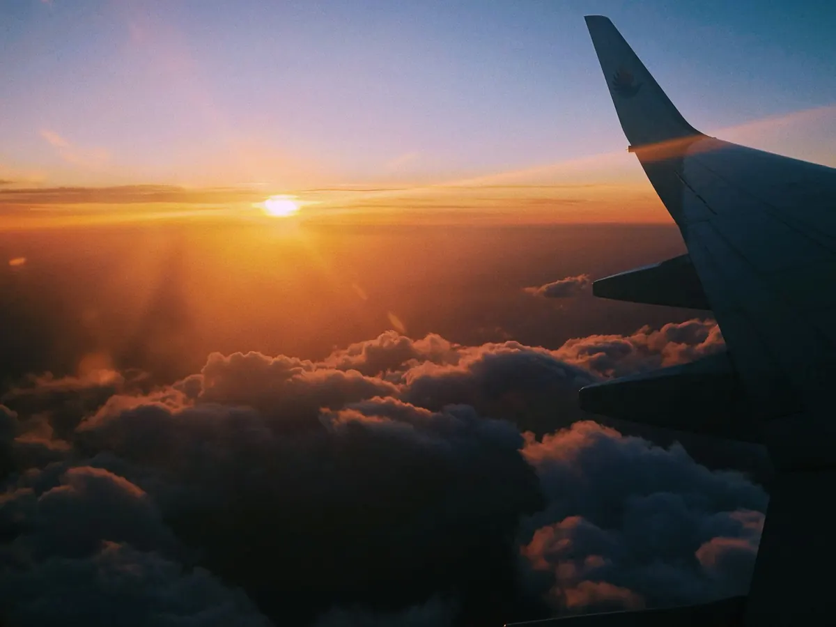 Aircraft wing above sunset clouds
