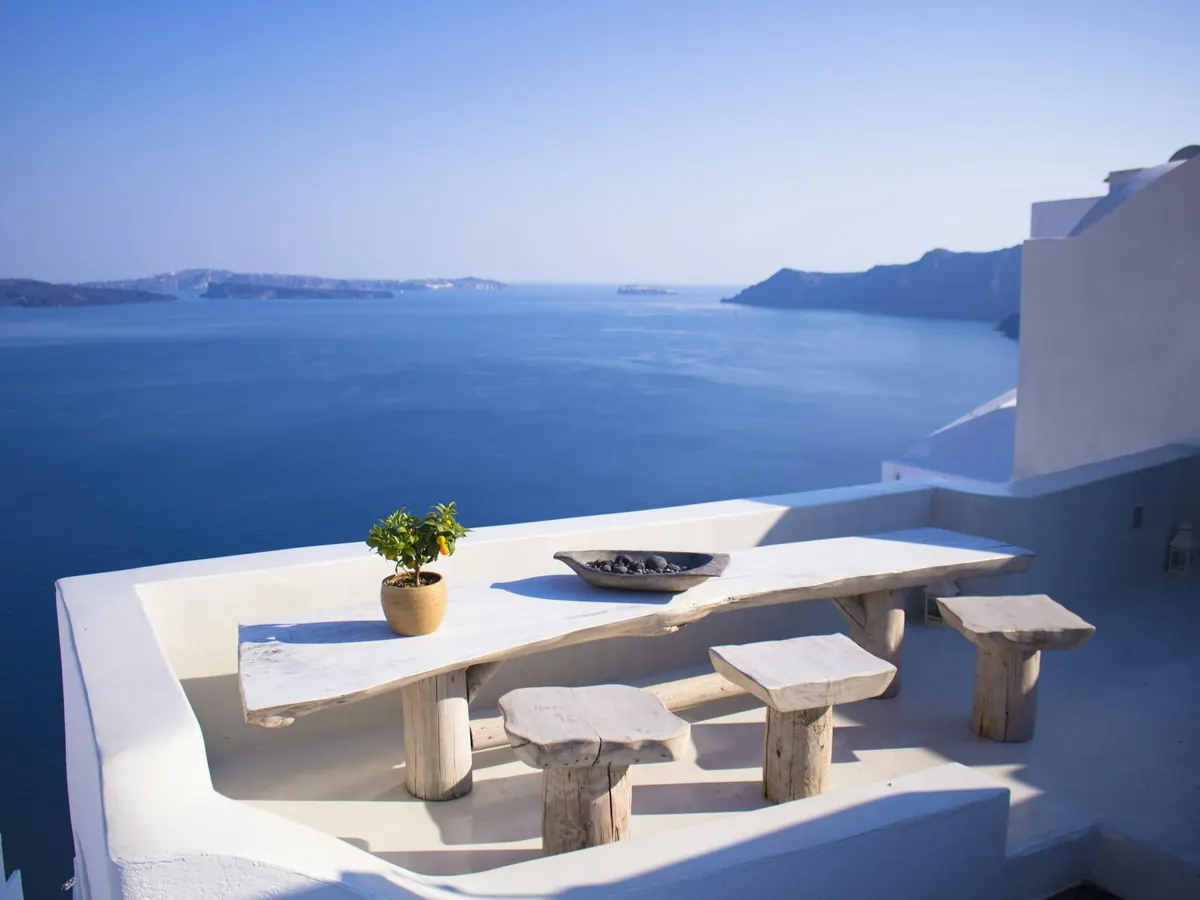 Whitewashed terrace table above a deep blue sea in the Cyclades
