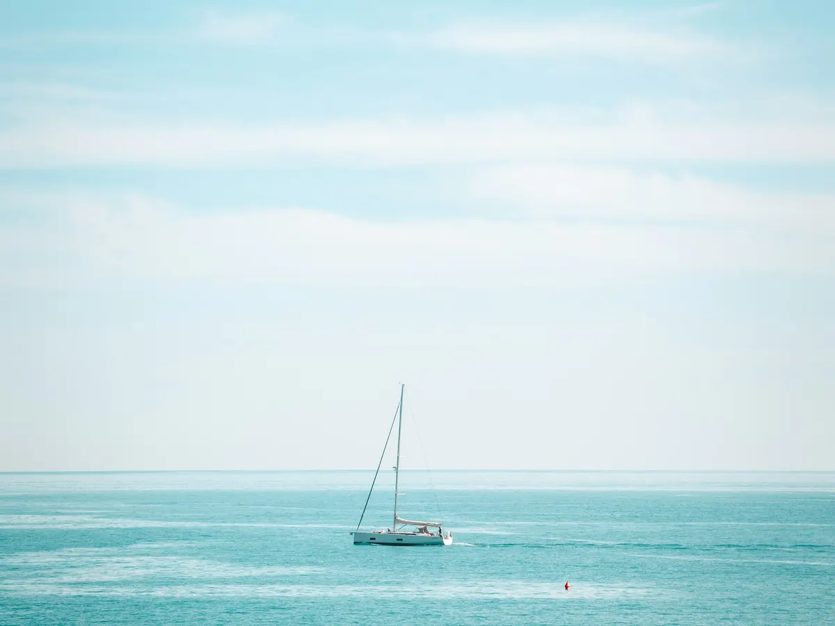 A lone sailboat on open turquoise water