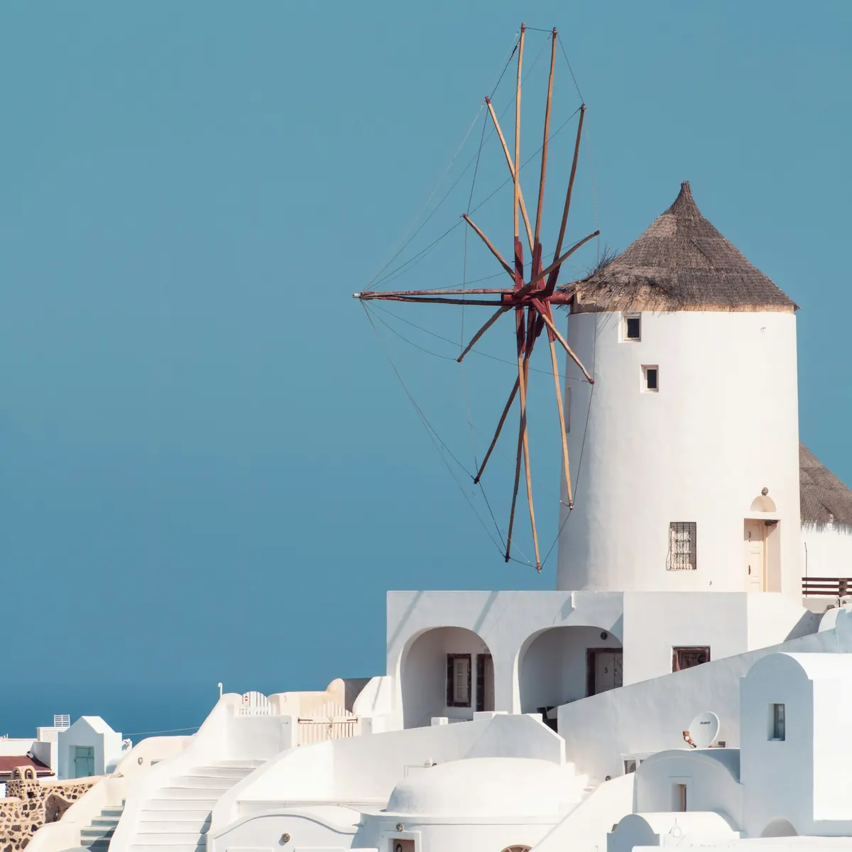 A whitewashed Mykonos windmill against a deep blue sky